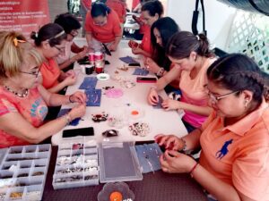 Mujeres integrantes de MUCPAZ participan en el taller de bisutería impartido por el IMC durante las actividades del Día Naranja en Lomas de la Selva.