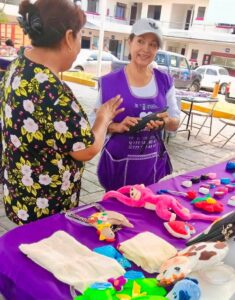 Emprendedoras participan en la Cooperativa Violeta organizada por el IMC en la explanada del Ayuntamiento de Cuernavaca, exhibiendo artesanías, alimentos y productos elaborados por ellas.