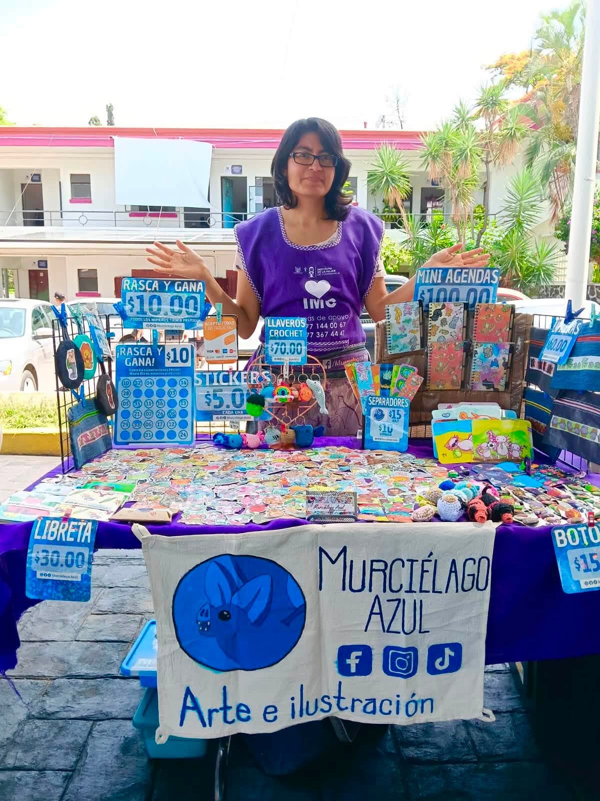 Emprendedoras participan en la Cooperativa Violeta organizada por el IMC en la explanada del Ayuntamiento de Cuernavaca, exhibiendo artesanías, alimentos y productos elaborados por ellas.