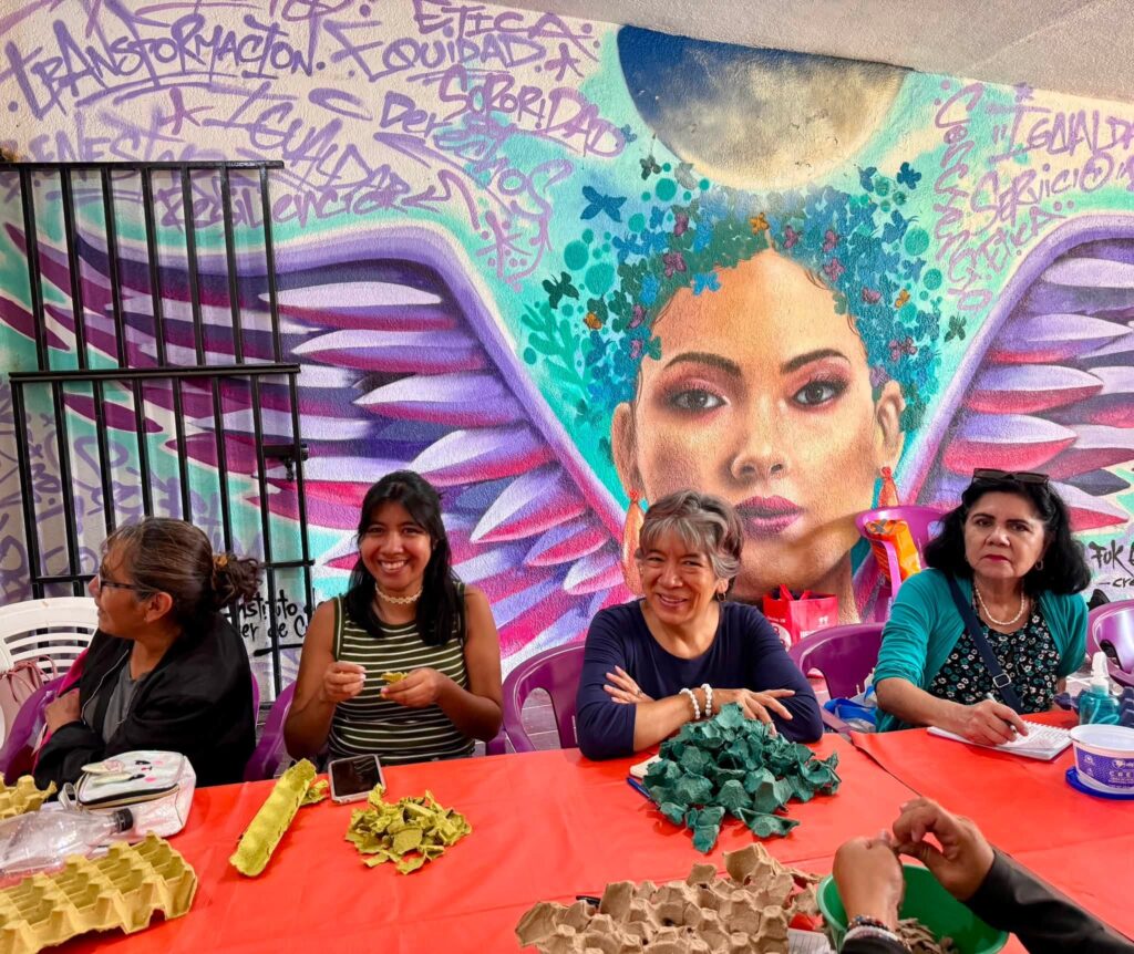 Usuarias del IMC participan en el taller de masa de papel, elaborando figuras decorativas con materiales reciclados como parte de una actividad de educación ambiental.